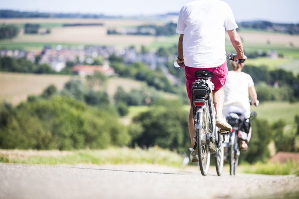 Man en vrouw fietsen op een dalende weg met op de achtergrond het glooiend heuvellandschap